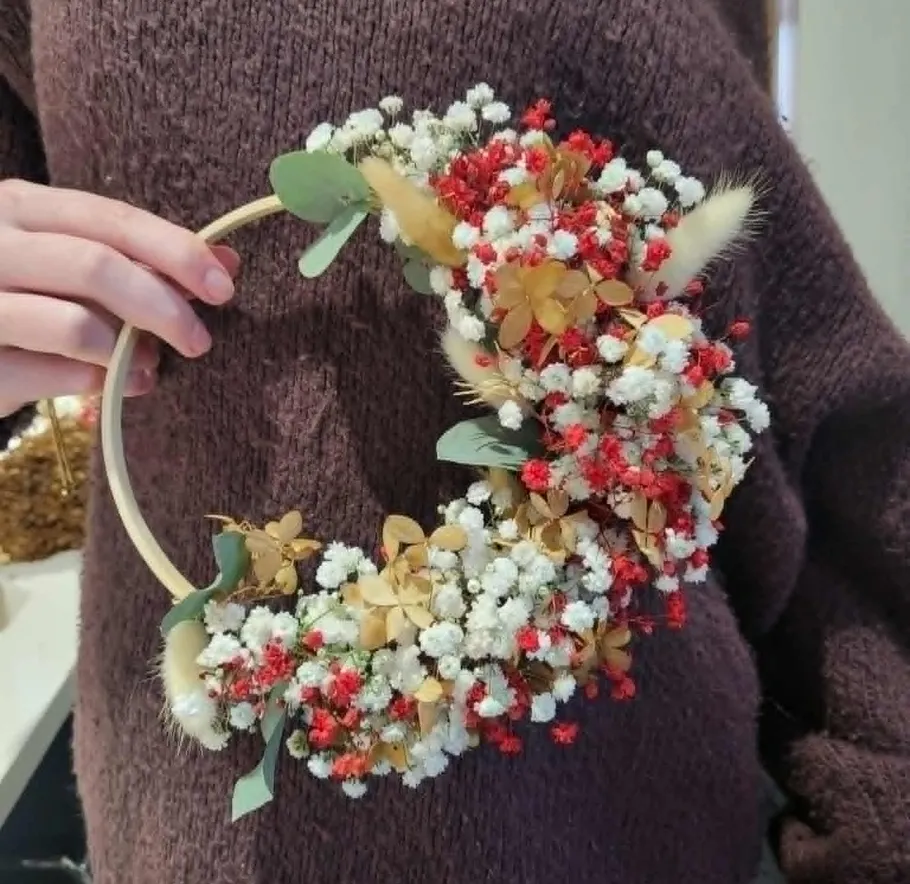 Person hält Blumenkreis mit kleinen Blumen.