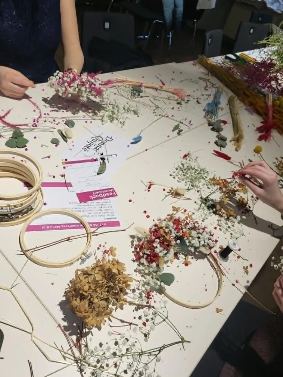 People crafting floral arrangements on a table.