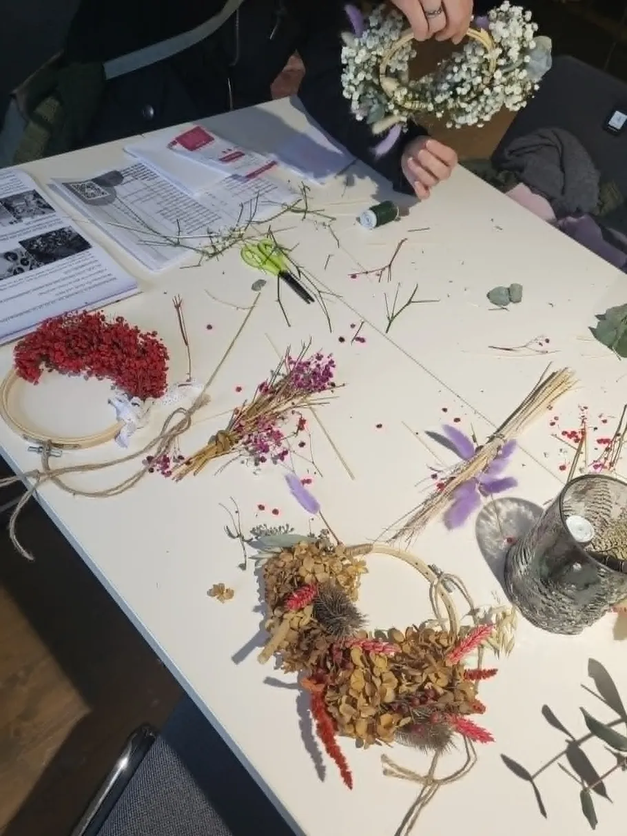 Personen basteln Kränze auf einem Tisch.