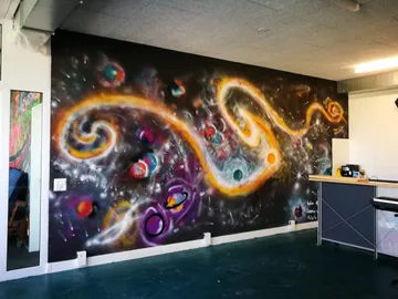 Wandmalerei zeigt bunte Galaxien und Planeten im Raum.