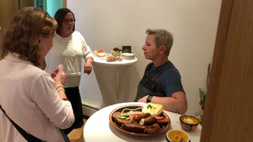 Gruppe von Frauen unterhält sich neben einem Buffet.