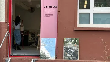 Woman enters studio with colorful workshop signs.