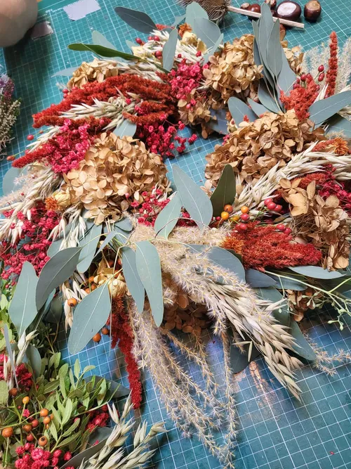 Getrocknete Blumen auf einem Basteltisch arrangiert.