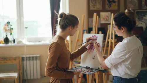 Two women painting together in art studio.