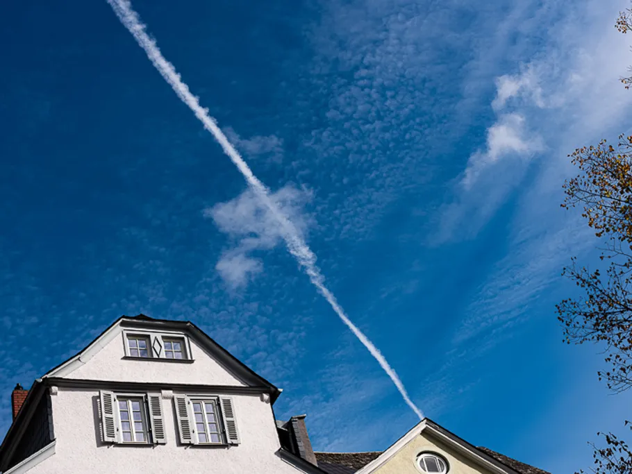 The house is under a blue sky with contrails.