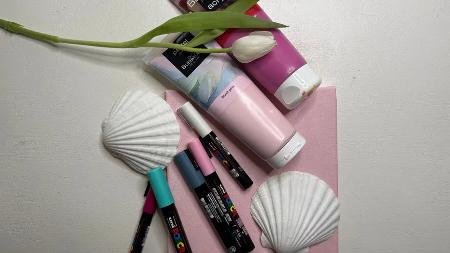 Art supplies arranged with tulip and seashells.