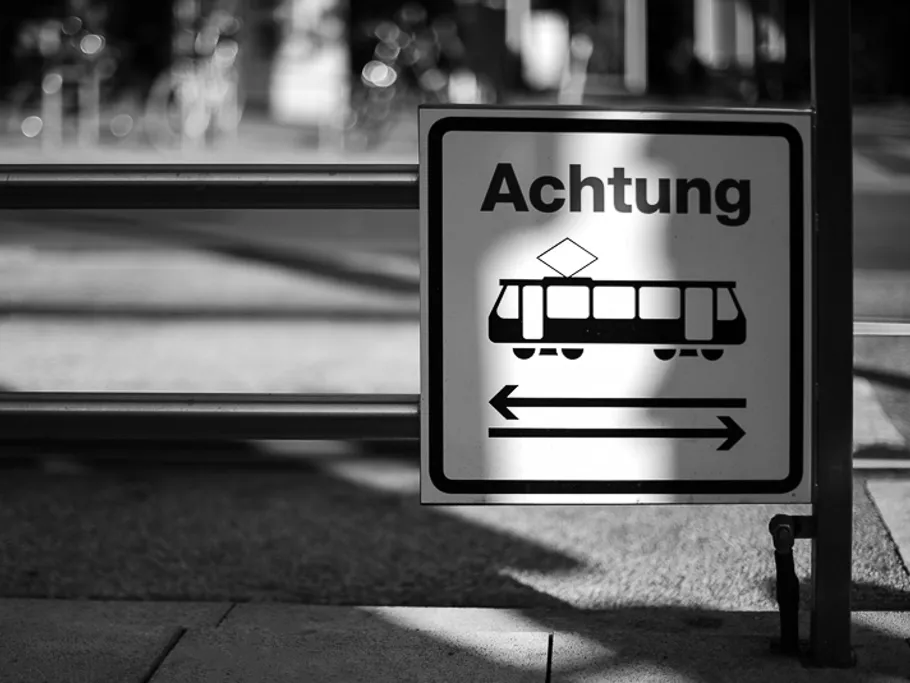 Achtung-Schild warnt vor herannahender Straßenbahn im Stadtbereich.
