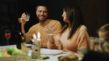 Paar lächelt beim Abendessen mit Getränken.