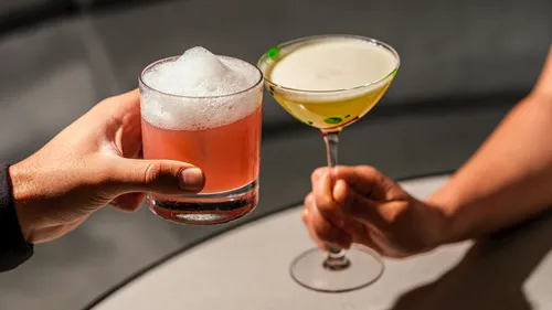 Zwei Cocktails werden drinnen angestoßen.