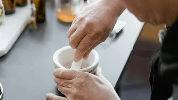 Person mahlt in einem Mörser auf Tisch.