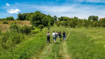 Menschen spazieren auf grasigem Weg auf dem Land.