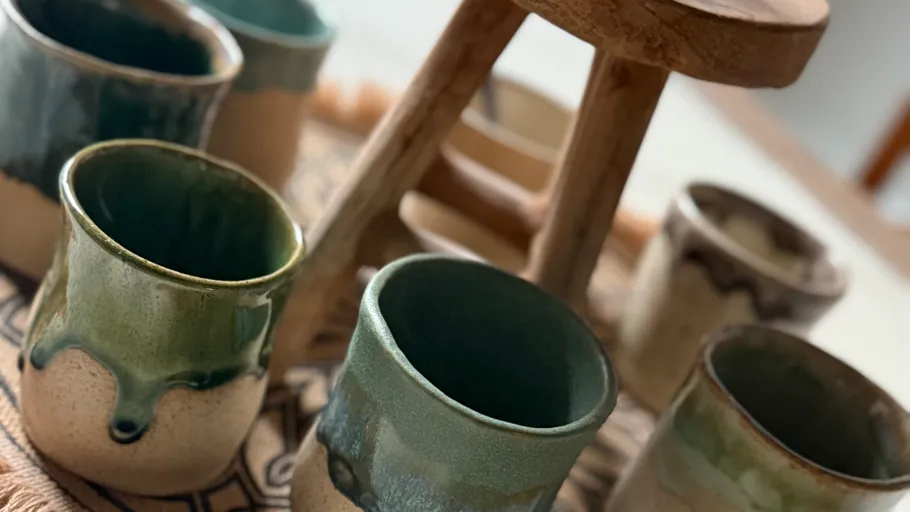 Bunte Keramikbecher auf einem Holzgestell.