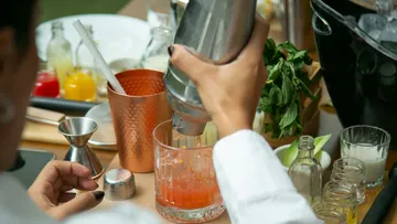 Person mixing a cocktail at a bar setup.