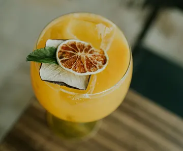 Orange cocktail with garnish on wooden table.