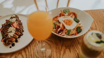Brunch mit Croissant, Eierspeise und Getränken auf Tisch.