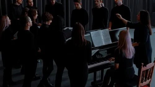 Gruppe singt um ein Klavier im Innenraum.