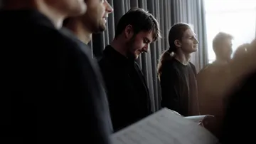 Group of people holding papers, standing together indoors.