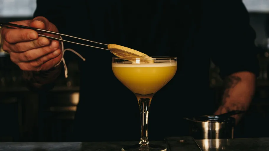 Bartender garnishing a cocktail with lemon slice.