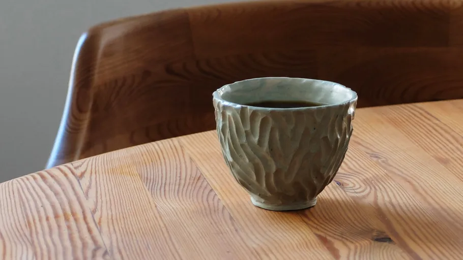 Ceramic cup with coffee on wooden table.