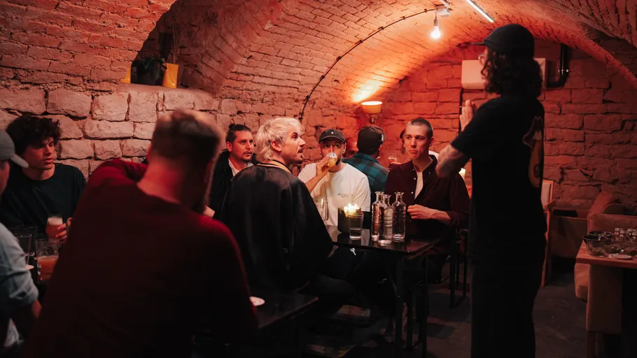 People sitting and talking in a dimly-lit brick room.
