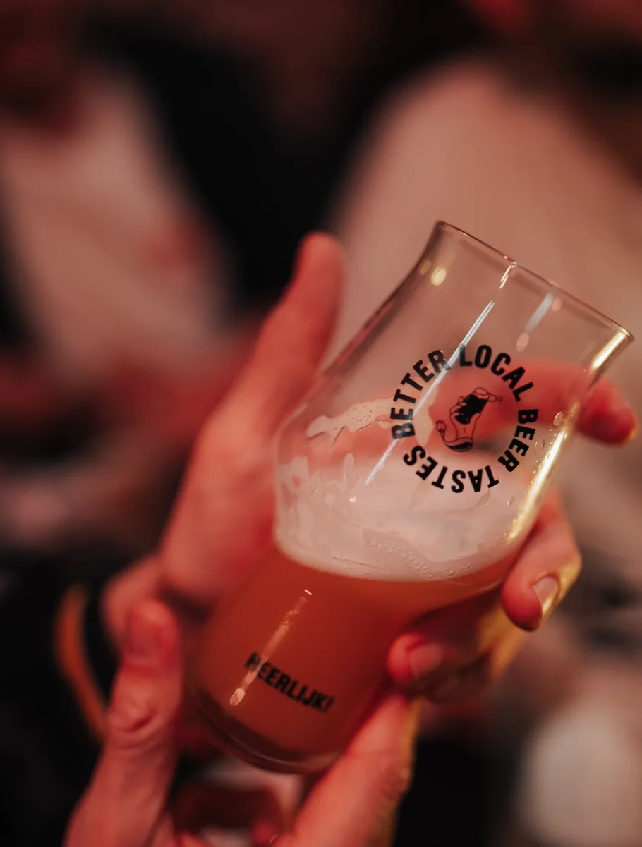 Glass of beer held in hand, bubbles visible.