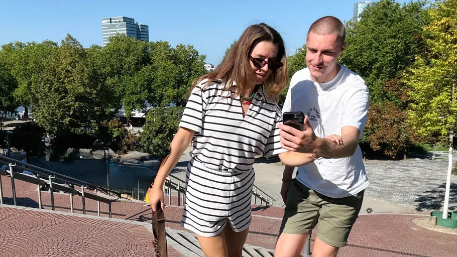 Two people looking at a phone outdoors.