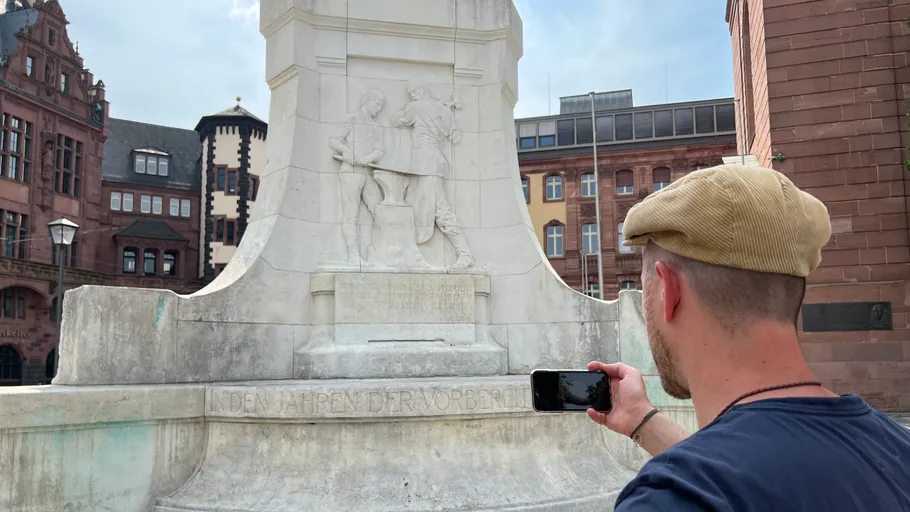 Man photographing monument with smartphone in city.