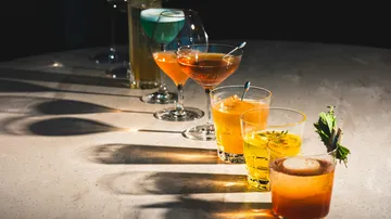 Verschiedene Cocktails auf einem dunklen Tisch.