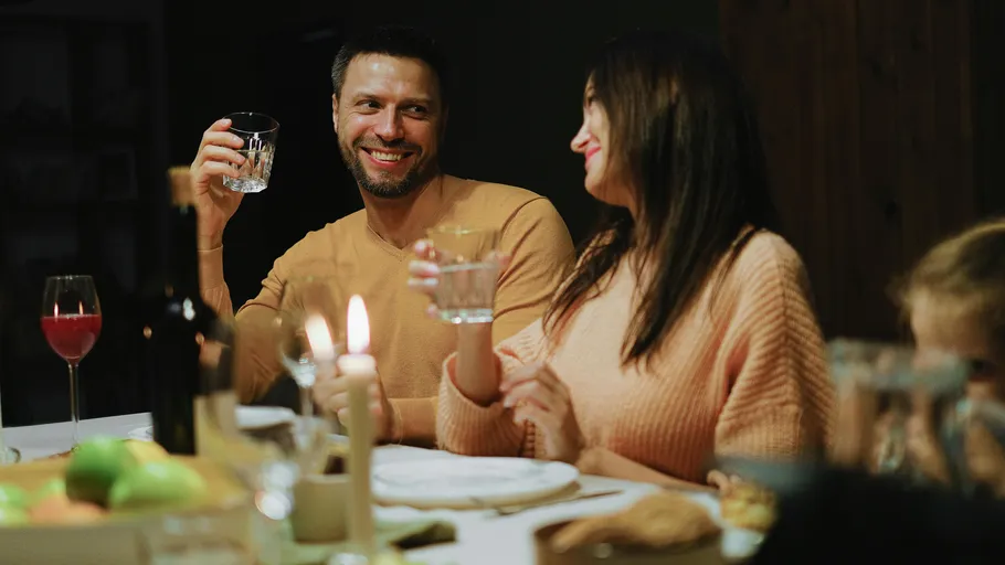 Two people enjoying drinks at candlelit dinner.