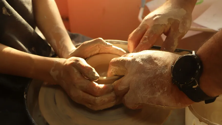 Hands shaping clay on a pottery wheel.