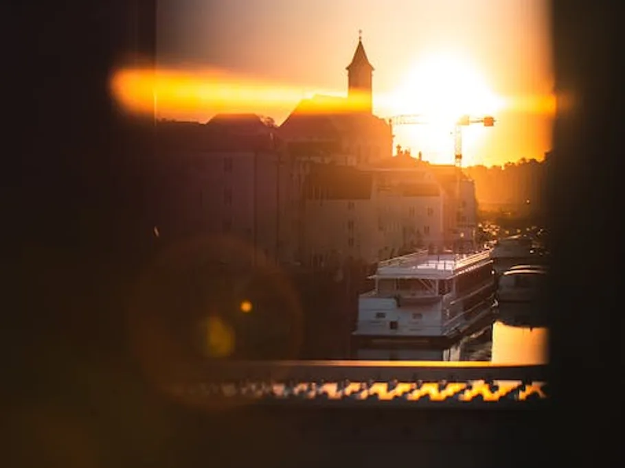 Boat passes buildings during sunset.