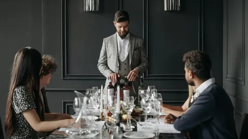 Man presenting wine to seated diners in restaurant.