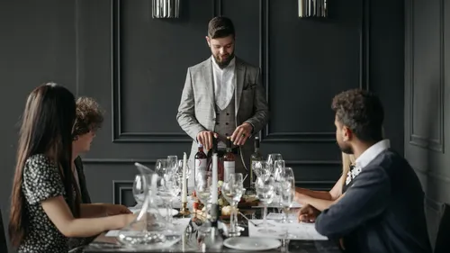 Kellner öffnet Wein an elegantem Esstisch.