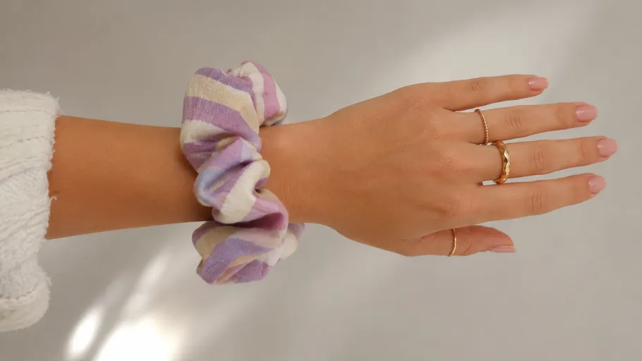 Hand with rings and scrunchie on wrist.