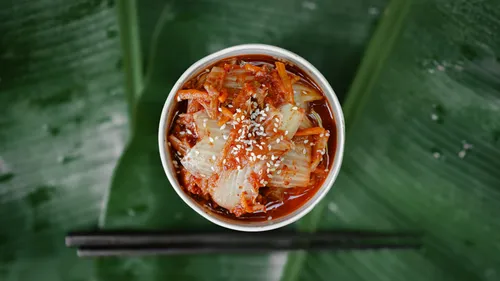 Kimchi mit Sesam auf blättrigem Hintergrund.