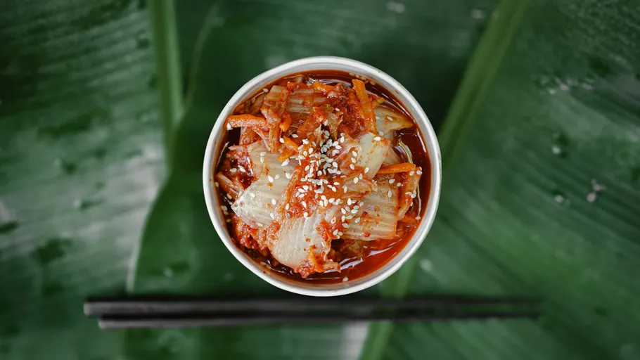 Kimchi mit Sesam auf blättrigem Hintergrund.
