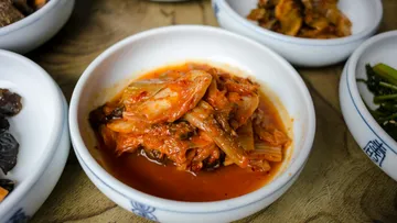 Kimchi in a bowl on wooden table.