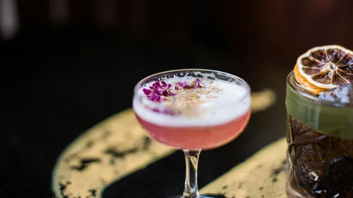Cocktail mit Schaumkrone auf dunklem Tisch.