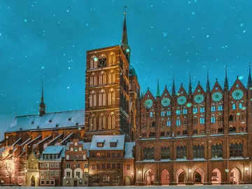 Historic building is covered by snow, illuminated at night.