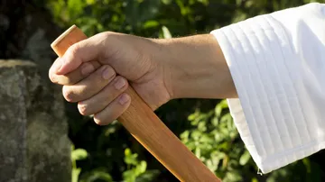 Hand hält Holzstab im Freien.