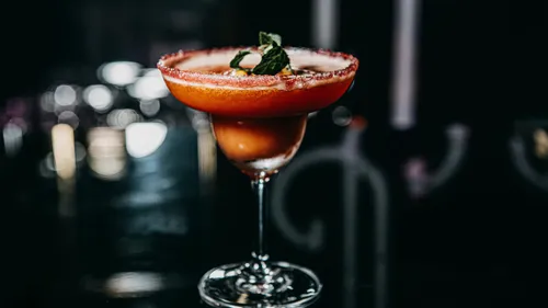 Cocktail im Glas mit Zuckerrand, dunkler Hintergrund.