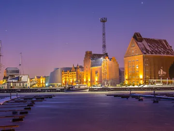 Harbour with illuminated buildings and a boat in the water.