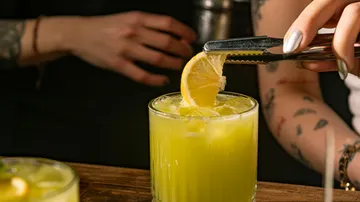 Zitronenscheibe auf leuchtendem Cocktailglas platziert.