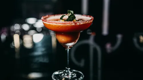 Cocktail in glass with sugared rim and mint garnish.