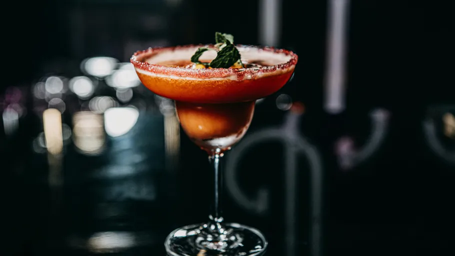Cocktail in glass with sugared rim and mint garnish.