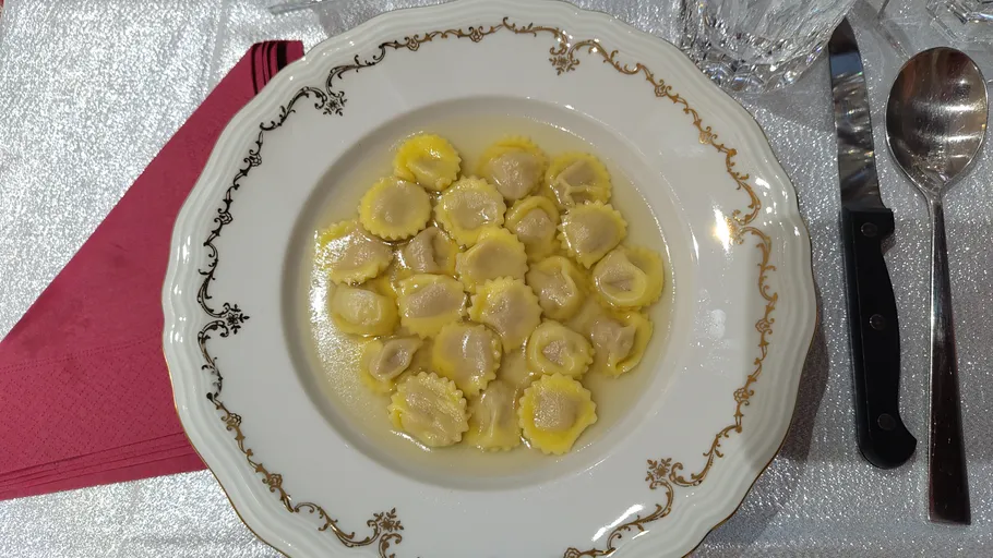 Ravioli in broth on a decorative plate.