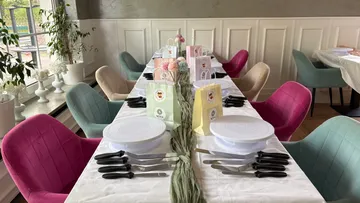 Table set for party with colorful chairs.