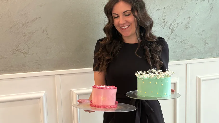 Woman holding two decorated cakes indoors.