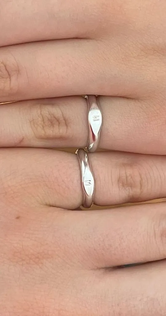 Two hands with matching silver rings.