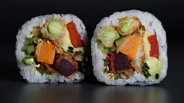 Two sushi rolls with various colorful vegetables.
